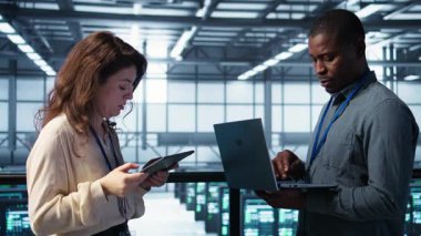 Sunucu çiftliğinde çalışan bir grup teknisyen verileri analiz etmek için dizüstü bilgisayar kullanıyor. Veri merkezindeki altyapıyı inceleyen ekip çalışanları, sistem bütünlüğü ve güvenliğinin sağlanması, kamera B