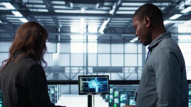 Bilgi işlem uzmanlarından oluşan bir ekip veri merkezinin kontrol evraklarını inceliyor, tabletteki yapay zeka teknolojisini kullanıyor. Sunucu çiftliğinde iş birliği yapan meslektaşlar, yapay zeka, kamera B, belge okuyorlar.