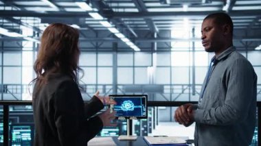 Veri merkezindeki mühendisler tablet entegre yapay zeka otomasyon araçlarıyla bakım yapıyorlar. Sunucu odasında çalışan takım arkadaşları yapay zeka ve B kamerasıyla