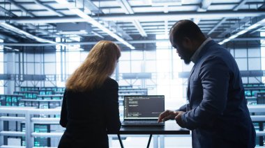 Veri merkezi donanım ömrünü uzatmak için dizüstü bilgisayar kullanarak bakım kontrolü yapan geliştiriciler. Sunucu hub sunucu altyapısındaki IT destek personeli not defteri, kamera B kullanarak sunucu izleme altyapısı