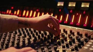 Ses teknisyenleri kontrol odasındaki amfi düğmelerini ve paneldeki tuşları çeviriyor. Parçaları karıştırmak ve ustalaştırmak için kurgu konsolunu kullanıyor. Müzik stüdyosunda profesyonel izleme mühendisi. Kamera B.