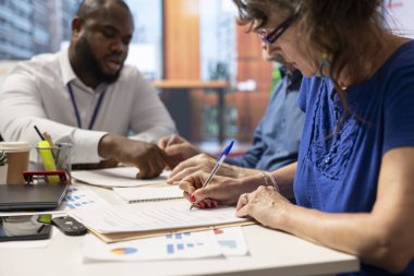 Yaşlı adam ve kadın komisyoncuyla bir toplantıda bankacılık sözleşmesi imzalarken emeklilik maaşlarını ve gelirlerini garantilemek için mükemmel bir emeklilik planı seçiyorlar. Belge şartlarını imzala.