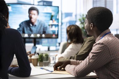 Genel müdür, kurum hedeflerine ulaşmak için en son proje güncellemelerini tartışmak üzere bir toplantı odasında uzaktan video bağlantısı üzerinden personelini kontrol ediyor. Profesyonel çalışma ekibi..