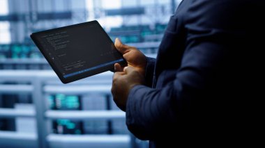 Yüksek teknolojili bir tesiste, ağ sorunlarını yamamak için tablet kullanarak yavaş veri aktarımı yapan bir mühendis. Sunucuların performansını ve bağlantısını etkileyen işçi düzeltme hatalarını kapat, kamera A