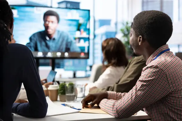Genel müdür, kurum hedeflerine ulaşmak için en son proje güncellemelerini tartışmak üzere bir toplantı odasında uzaktan video bağlantısı üzerinden personelini kontrol ediyor. Profesyonel çalışma ekibi..