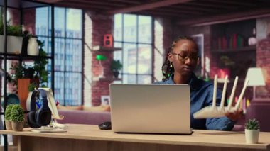 Afrikalı Amerikalı bir kadın kablo çekerek internet sağlayıcısından destek alarak kablosuz internet modemini yeniden başlatıyor. Devam eden Wi-Fi bağlantı sorunları. Kamera B.