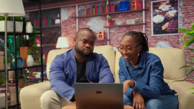 Afrikalı Amerikalı çift, iş eğilimlerini araştırmak ve çevrimiçi bir markayı yönetmek için bir dizüstü bilgisayar kullanarak bağımsız çalışma projesi üzerinde çalışıyor. Uzaktan kumandalı başarılı kariyer gelişimi. Kamera A.