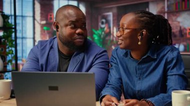 Evden uzakta bir web sitesine katılan siyahi bir adam ve kadın dizüstü bilgisayarlarında kulaklıklarla internet kurslarını dinliyorlar. Genç çiftler yeteneklerini geliştirmek için dijital aletler kullanıyorlar. Kamera.
