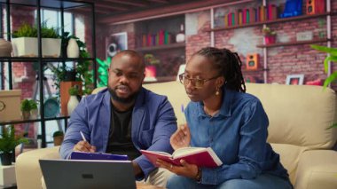 Yetişkin insanlar sehpada program ve planlama faaliyetlerini denetliyor, online araçlarla zaman yönetimi üzerinde çalışıyor. Defter kullanan ve el yazısı notlar alan bir çift. Kamera A.