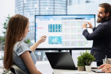 Finansal danışman, gençlerin yatırım portföylerini çeşitlendirmesine yardımcı olmak için büyük ekranda sunum yapıyor. Ajan, Z gen kızına hisse senetleri, tahviller ve diğer varlıkların karışımını sağlamak için büyük ekranı kullanır