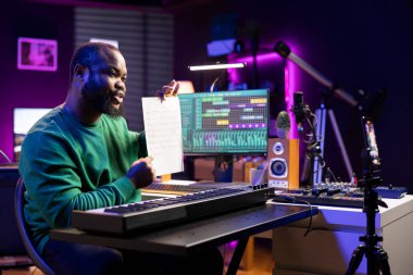 Sanatçı piyano notalarını açıklamak için notalara işaret ediyor, ev stüdyosunda insanlara sentezleyici çalmayı öğretiyor. Ünlü besteci müzisyen, online master dersinde midi denetleyicisini çalıyor..