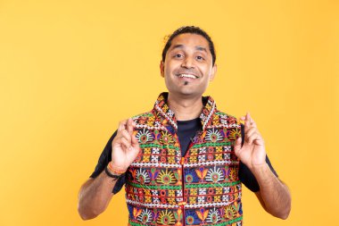 Mutlu adamın portresi parmaklarını çapraz yapıp dilek tutuyor, stüdyo arka planında soyutlanıyor. Neşeli insan gülümsüyor ve iyi şanslar diliyor. El hareketi, mucize bekliyor.