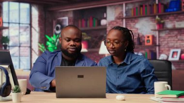 Siyahi serbest çalışan çift başarılarını kutlamak için beşlik çakıyor ve başarılı bir proje için görevlerini tamamlıyorlar. Genç adam ve kadın iş birliklerinden memnunlar. Kamera B.