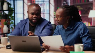 Siyahi insanların her ikisi de görev yönetimi için bilgisayarlarında online araçlar kullanarak belirlenen ofislerinde çalışırlar. Konforlu evlerinden işlemleri verimli bir şekilde tamamlıyorlar. Kamera B.