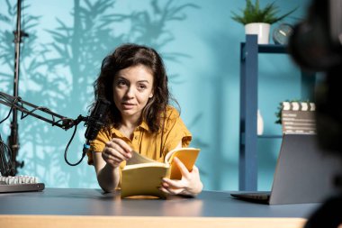 Stüdyoda gülümseyen internet yıldızı yayınevinden yeni çıkan ciltli kitabı eleştiriyor. Adaylar için yazarın yeni romanını sunan ve okuyan neşeli kadın, kitabı tanıtıyor.