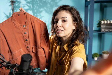 İçerik yaratıcısı izleyicilere hızlı moda ceketini sunuyor, akıllı telefon özçekim kamerasıyla çekim yapıyor. Moda vlogcusu aboneleri alışverişe çağırıyor, sponsorlu ürünü destekliyor