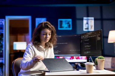 Bilgisayar monitörleriyle karşılaştırıldığında şirketin güvenlik açığını bulmak için dizüstü bilgisayar kullanan bir siber güvenlik uzmanı. Geliştirici dizüstü bilgisayara güçlendirilmiş kod yüklüyor, PC ekranları ile karşılaştırılıyor