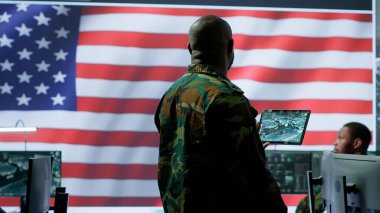 Yüksek teknoloji ofisindeki askeri personel dünya haritasındaki gözetleme faaliyetlerini ve uydu görüntülerini takip ediyor. Amerikan Ordusu personeli tehditlere karşı ulusal koruma sağlıyor. Kamera A.