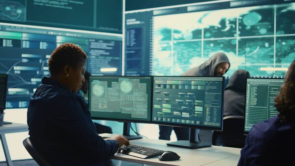 Governmental hackers analyzing big data for cyber threat detection, working at agency desks. Professional expert woman analyzes cyber intelligence and prevention of digital threats. Camera B.