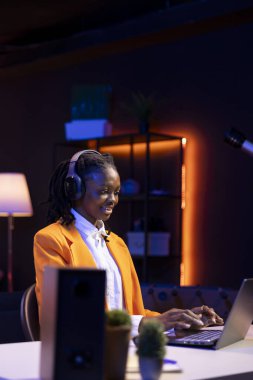 Neşeli ev sahibi dizüstü bilgisayarını komedi filmleri izlemek için kullanıyor, komik şakalara gülüyor. Ev sinemasında mutlu bir kadın mizahi film sahnesiyle eğleniyor.