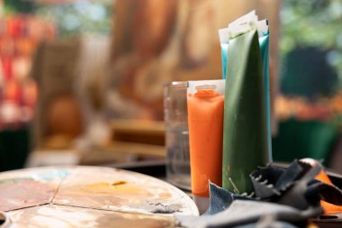 Modern boya malzemeleri ve boyama tüpleri ya da atölyedeki yağlı boyalar, fırça takımı ve boş atölyede sanat ve zanaat hobisi yaratmak için kullanılan renkli pigmentler. Kapat..