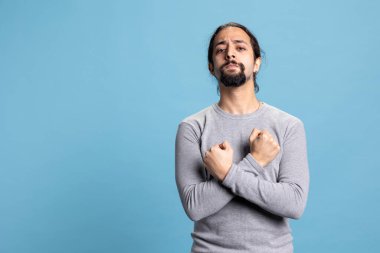 Stüdyoda kollarını göğsünde kavuşturarak poz veren ciddi bir insan kararlı davranıyor ve gücünü gösteriyor. Kendine güvenen soğukkanlı bir adam arka plana karşı güçlendirmeye odaklanmış..