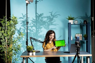 Stüdyodaki gülümseyen kadın kırık tabletin bakımını nasıl yapacağına dair teknik dersleri filme alıyor. Neşeli çevrimiçi şov sunucusu abonelerine izole edilmiş ekran dijital aygıtının nasıl açılıp tamir edileceğini öğretiyor