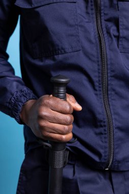 Alışveriş merkezinin güvenlik ajanı, işte kendi güvenliği için copunu tutuyor. Binayı koruyor ve koruyor. İş üniformalı profesyonel koruma stüdyoda tetikte bekliyor. Kapat..