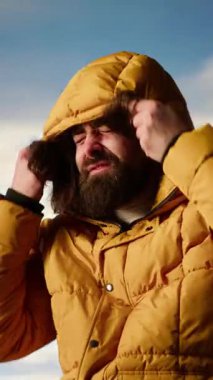 Dikey Video Maceracısı aşırı rüzgarlı havada dağa tırmanıyor ve başarısından memnun. Genç yürüyüşçü tepenin üstünde soğuk rüzgarı hissediyor, manzaralı arka plan. Kamera B.