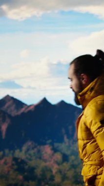 Dikey Video Yürüyüşçüsü, dağların panoramik manzarasına hayran olmak ve uzaklığı ve manzarayı seyretmek için bir dakika alır. Temiz hava, manzaralı arka plan ve bir kaşif için huzurlu bir ortam. Kamera.