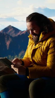 Dikey Video Camper, yüksek irtifada bir kamp alanında tablet kullanarak daha iyi sinyal arayarak ve güvenliğini riske atarak güçlü bir rüzgarla savaşıyor. Tehlikeli dağ sıraları soğuk hava. Kamera A.