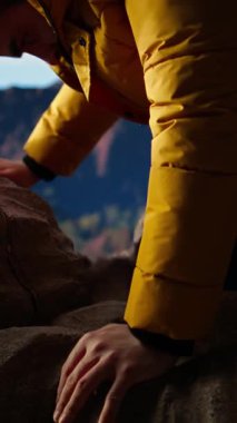 Dikey Video Gururlu kaşif, engebeli tepeler ve dramatik bulutlarla çevrili yüksek rakımlı bir dağın zirvesinde kutlama yapıyor. Zafer pozu başarıya tırmanmanın heyecanını yakalar. Kamera A.