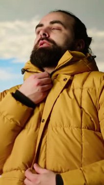 Dikey Video Dağı yürüyüşçüsü, zirveye tırmandıktan sonra ceketinin fermuarını çekerek geniş bir tepe ve gökyüzü manzarasıyla vahşi doğada yolculuk macerasını kucaklıyor. Açık hava keşfi