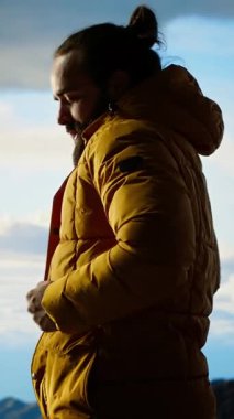 Dikey Video Erkek Yürüyüşçüsü kayalıklardaki nefes kesici dağ manzarasını, manzaranın tadını, temiz havayı ve engebeli zirveleri alıyor. Yeni ufuklar keşfetme heyecanı. Kamera B.