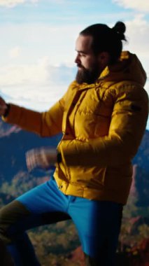 Dikey Video Doğa Aşığı bir dağın tepesinde durup vahşi doğanın güzelliğini özümserken kendi fotoğraflarını çekiyor. Yüksek irtifa macerası dayanıklılığı ve kişisel gelişimi, fotoğrafçılığı sembolize eder