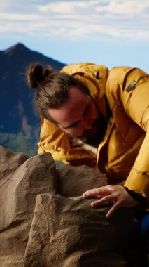 Zirvede duran Dikey Video Kararlı Dağcı huzurlu bir başarı anının tadını çıkarıyor. Uçsuz bucaksız gökyüzü, dağ sıraları ve temiz hava özgürlüğün, refahın ve keşiflerin özünü vurguluyor. Kamera.