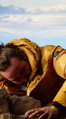 Dikey Videolu Genç Gezgin kalın giysiler içinde derin bir tatmin duygusuyla zirveye ulaşır, çok yorgun ama başarısından gurur duyar. Maceracı bir hedefe ulaşıyor. Kamera B.