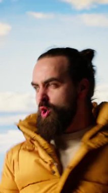 Dikey Video Yürüyüşçüsü dağın zirvesine ulaşır ve başarılı bir tırmanışın ardından zafer pozu verir. Bu da maceraya olan güveni yansıtır. Gezgin fethetmenin kişisel başarısının tadını çıkarıyor.