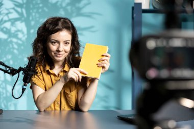 Mutlu çevrimiçi program sunucuları yılın en iyi eleştiri kitaplarını okuyor ve öneriyor. Stüdyodaki neşeli içerik yaratıcısı ilgilenen okuyucular için özetler hazırlıyor, profesyonel mikrofon ile konuşuyor.