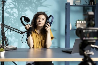 Teknik uzman, apartman dairesindeki kablosuz kulaklıkları inceleyip özelliklerini karşılaştırıyor. Sosyal medya takipçileri için video kaydedecek, dinleme cihazlarını analiz edecek