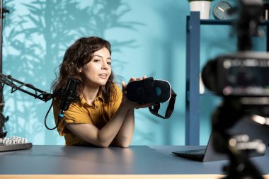 Seyircilere sanal gerçeklik gözlüğü takan gülümseyen kadın profesyonel kamerayla video çekiyor. Hayranlarına önermeden önce sanal gerçeklik kulaklığı ürünü deneyen iyimser içerik yaratıcısı