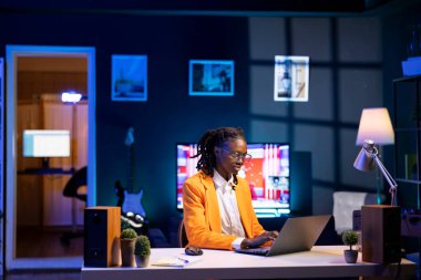 İşçi masadaki veri tablolarını analiz ediyor, istatistiksel grafikleri yorumluyor, eğilimleri tanımlıyor, analitik raporları derliyor, bilgiyi işlemek ve görselleştirmek için veri analiz yazılımı kullanıyor