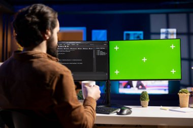 Programcı sıcak içecek içiyor ve yeşil ekran bilgisayarı kullanarak şirket ağını devre dışı ve beklenmedik sistem arızalarından koruyor. Elinde kahve fincanı olan bir yönetici. Bilgisayarın önünde.
