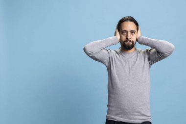 Orta Doğulu adam, üç bilge maymun illüstrasyonunun bir parçası olarak kulaklarını kapatıyor ve stüdyodaki ahlaki motivasyon deyimini sergiliyor. Geleneksel bilgelik metaforuyla hiçbir kötülük duymayan genç..
