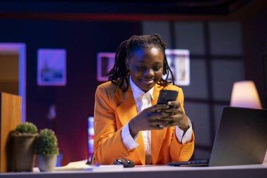 Neşeli genç cep telefonundan mesajlar okuyor, iyi haberler aldıktan sonra mutlu oluyor. Neon ışıklı dairedeki gülümseyen kadın akıllı telefondaki SMS 'ten etkilenmiş, arkadaşlarıyla sohbet ediyor.