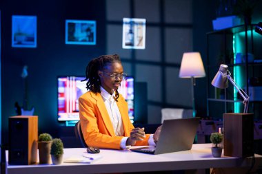 Ev ofis masasında dizüstü bilgisayar kullanan, sunum slaytlarını hazırlayan, grafikleri yerleştiren, düzenleri ayarlayan, özetleri yazan, dosyaları kaydeden, sunum malzemelerini paylaşılan sürücülere yükleyen bir kadın.