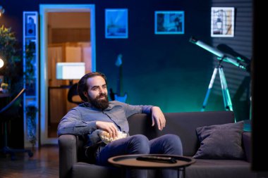 Gülümseyen kordon kesicisi TV 'nin önündeki koltukta oturmuş film seyrediyor. Memlekette televizyon seyreden neşeli insan talep kanalında şovlu video gösteriyor.