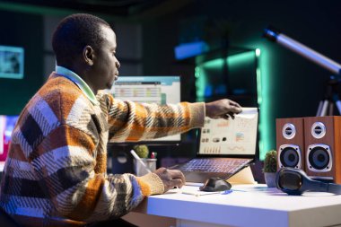 Afrikalı Amerikalı danışman bilgisayarına bir hafıza notu yapıştırıyor ve günlük finansal görevlerini çözmesi için yapışkan kağıtlarla bir hatırlatma oluşturuyor. Muhasebe danışmanı evde çalışıyor..