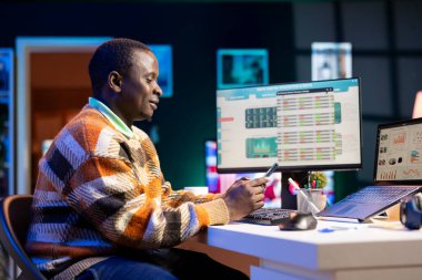 Siyahi bir çalışan mesajlara cevap veriyor ve akıllı telefonuyla sosyal medyayı kontrol ediyor. Finans ve muhasebe işlerine ara veriyor. Uzaktan kâr büyümesi planlayan yetenekli bir danışman.