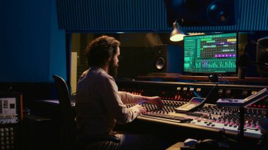 Kontrol odası ses mühendisi sürgülü ve düğmeli müzik düzenliyor, profesyonel ses geçirmez stüdyoda post prodüksiyon üzerinde çalışıyor. Müzik seti karıştırma konsolunda şarkı üreten teknisyen. Kamera B.